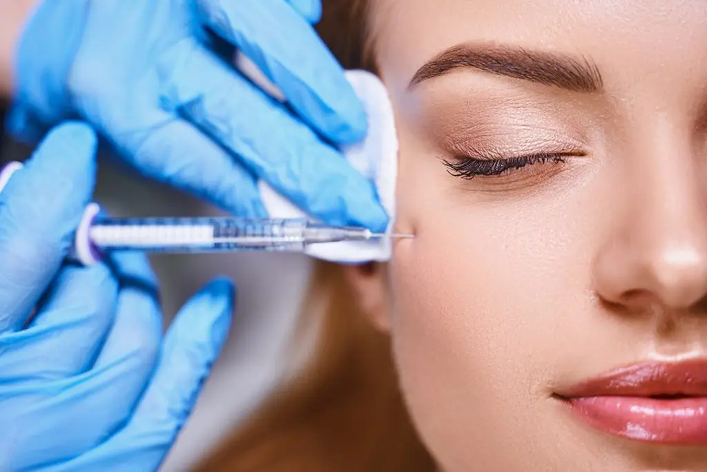 Young female is preventing wrinkles on her face by getting a liquid facelift.