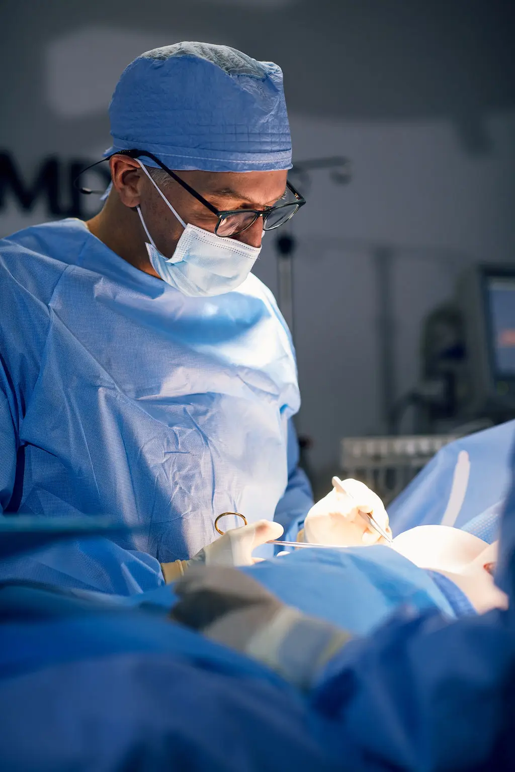 Dr. Peter Capizzi board certified plastic surgeon in operating room completing a breast augmentation